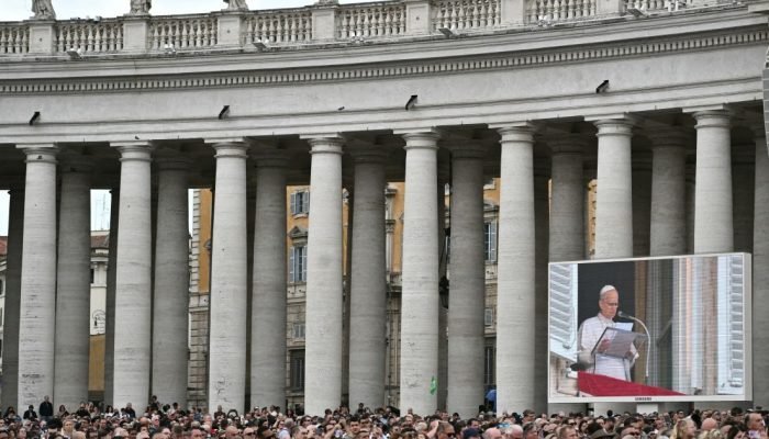 Pessoas ouvem o Papa Leão XIV na Praça de São Pedro durante a oração do Angelus, um dia apó...