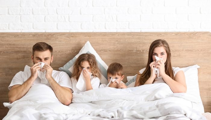 Family ill with flu in bed at home