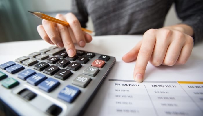 Closeup of accountant counting on calculator and working with table