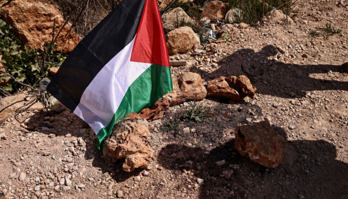 Uma bandeira palestina é colocada no local onde um ataque de colonos judeus matou 3 palestinos e...