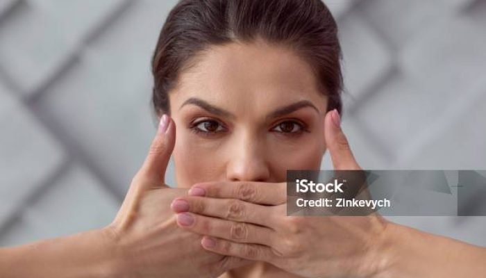 Be silent. Portrait of a sad cheerless young woman covering her mouth while being silent