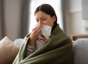 sick-young-woman-wrapped-blanket-blowing-her-nose-768x512